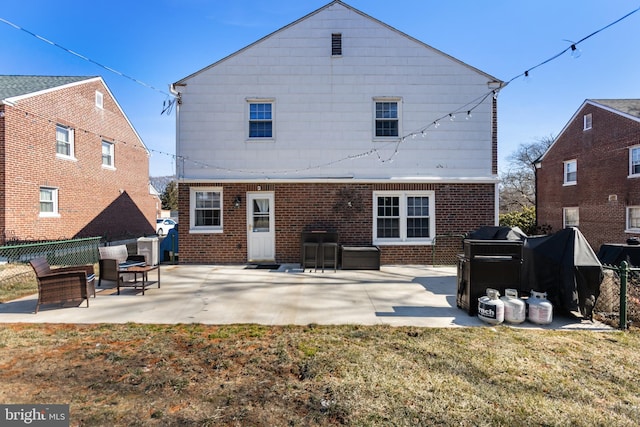 rear view of house featuring a patio, brick siding, a lawn, and fence