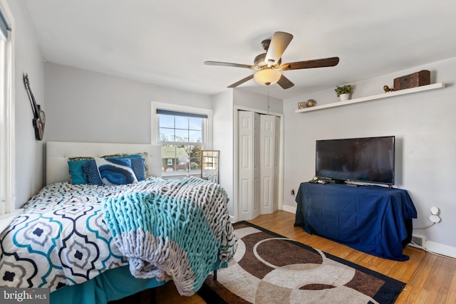 bedroom with a closet, ceiling fan, baseboards, and wood finished floors