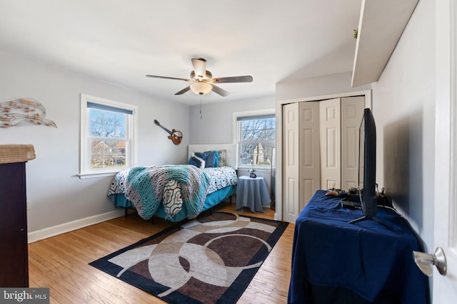 bedroom with a closet, wood finished floors, a ceiling fan, and baseboards