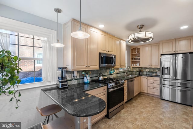 kitchen featuring a sink, a kitchen breakfast bar, appliances with stainless steel finishes, open shelves, and decorative light fixtures