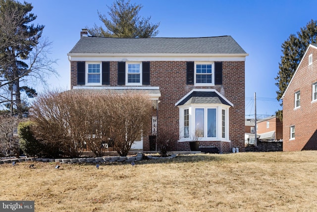 traditional home featuring a front lawn and brick siding