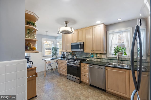 kitchen with a sink, appliances with stainless steel finishes, open shelves, dark countertops, and decorative light fixtures