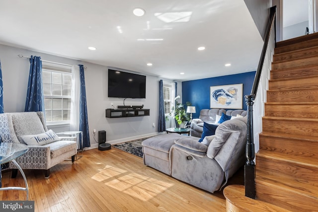 living room featuring stairs, baseboards, wood finished floors, and recessed lighting