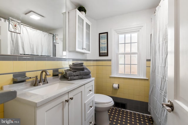 bathroom with visible vents, toilet, tile patterned flooring, vanity, and tile walls