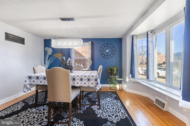 dining area featuring a wealth of natural light, baseboards, visible vents, and wood finished floors