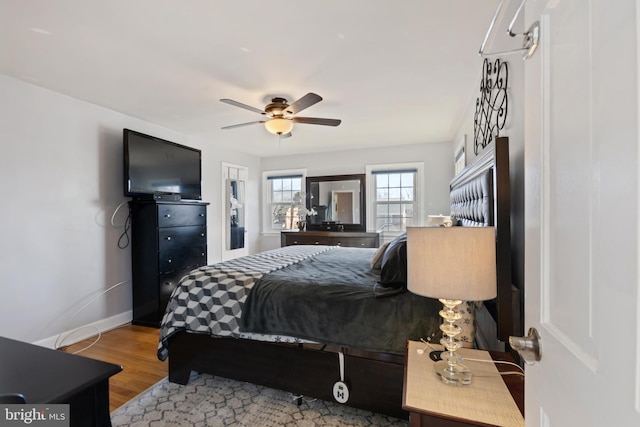 bedroom featuring a ceiling fan, baseboards, and wood finished floors