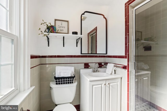 full bathroom with toilet, vanity, tile walls, wainscoting, and a stall shower