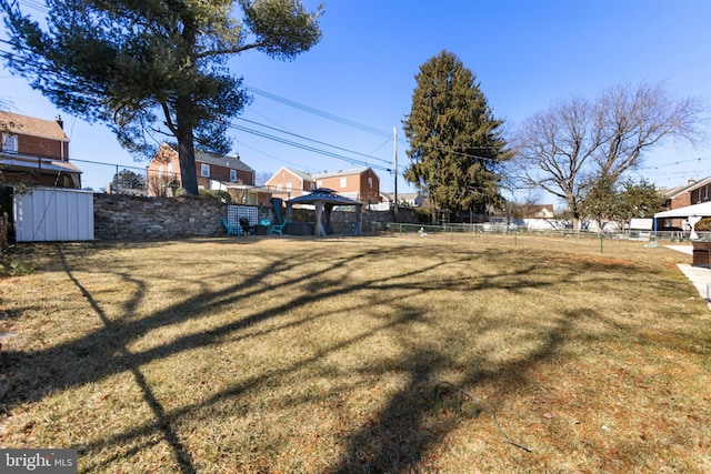 view of yard featuring a gazebo, a fenced backyard, and a residential view