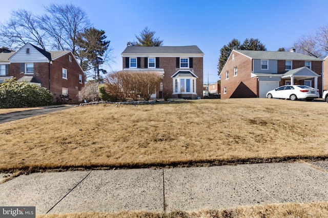 view of front facade with a front yard, a residential view, and brick siding