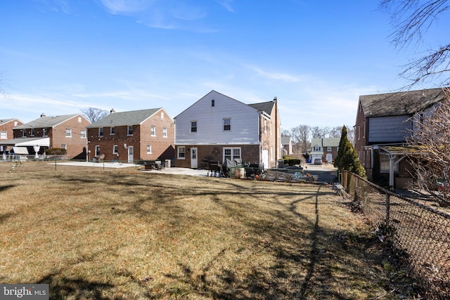 rear view of property featuring a residential view, a patio area, a fenced backyard, and a lawn