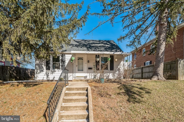 bungalow-style house featuring a porch, a front lawn, and fence