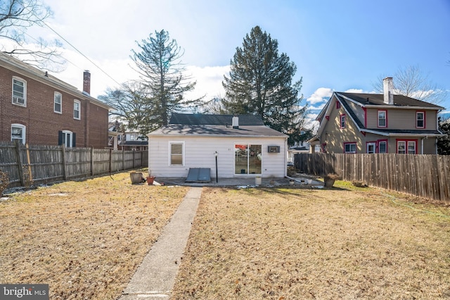 rear view of house featuring a fenced backyard and a lawn