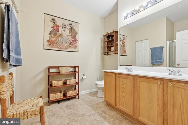 bathroom featuring double vanity, a stall shower, baseboards, toilet, and a sink