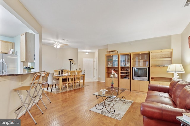 living area featuring light wood-type flooring, visible vents, ceiling fan, and baseboards