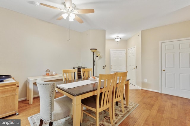 dining room featuring light wood-style flooring, baseboards, and a ceiling fan