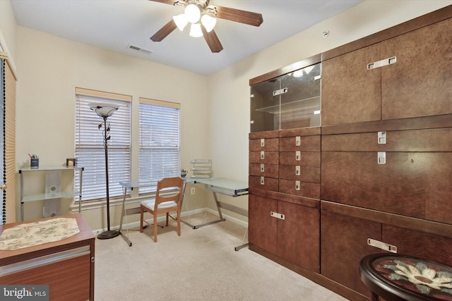 home office featuring baseboards, ceiling fan, visible vents, and light colored carpet