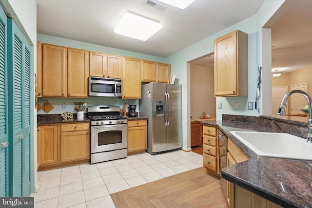 kitchen featuring visible vents, stainless steel appliances, light brown cabinetry, a sink, and light tile patterned flooring