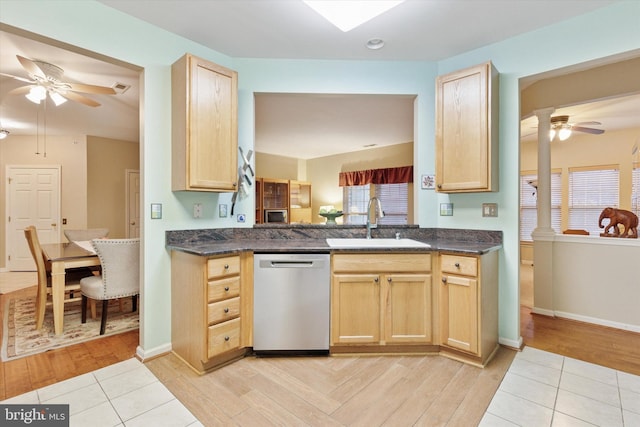 kitchen featuring dark countertops, light brown cabinets, dishwasher, and a sink