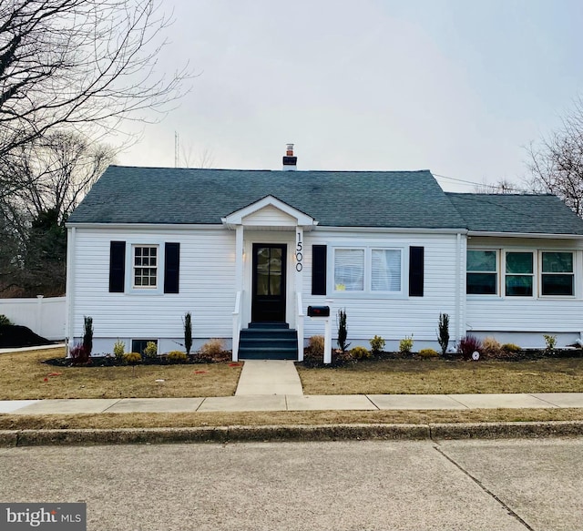 view of front of property featuring a front yard, roof with shingles, a chimney, and entry steps