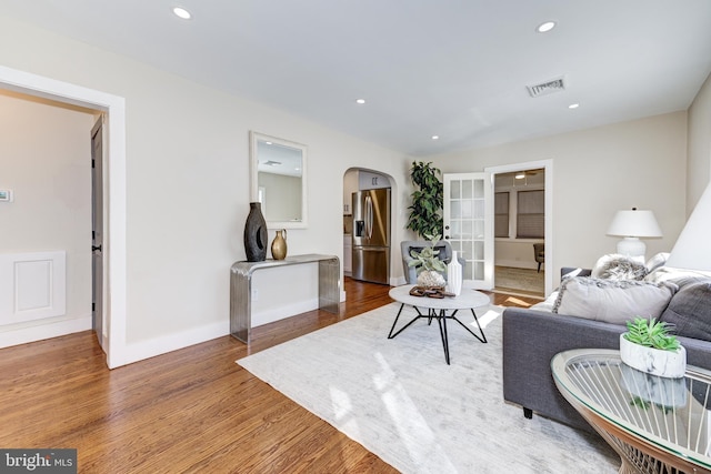 living area with recessed lighting, visible vents, arched walkways, and wood finished floors