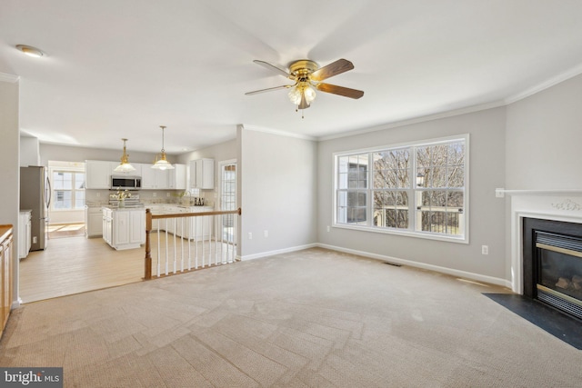 unfurnished living room featuring visible vents, a fireplace with flush hearth, crown molding, and baseboards