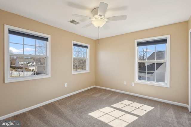 carpeted empty room featuring visible vents, baseboards, and a ceiling fan