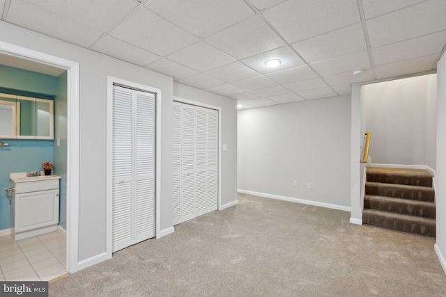 finished below grade area with a drop ceiling, stairs, baseboards, and carpet floors