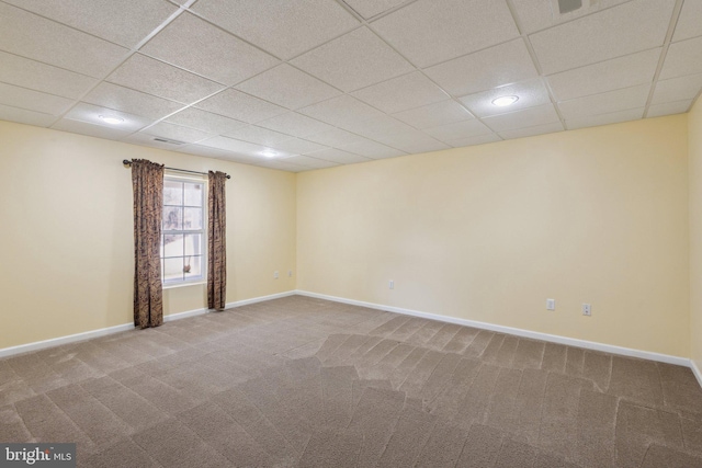 carpeted empty room featuring a paneled ceiling and baseboards