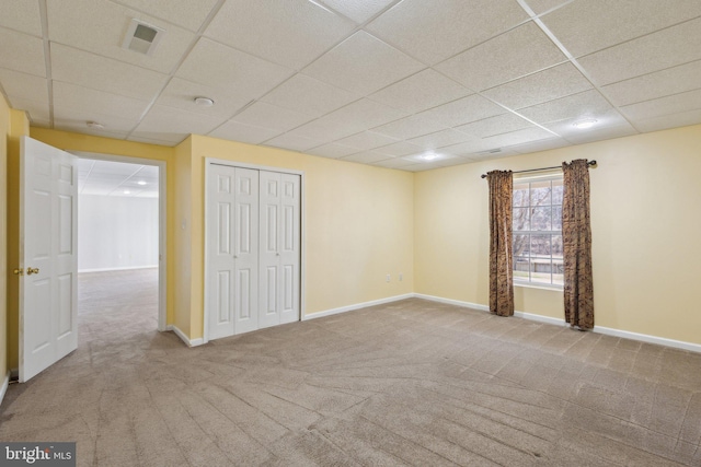 unfurnished bedroom featuring a drop ceiling, visible vents, baseboards, and carpet