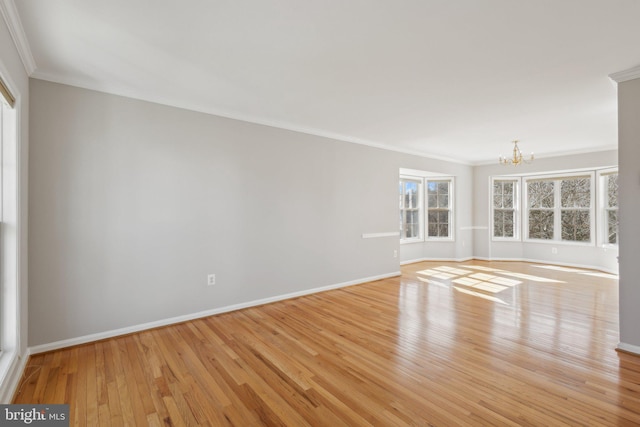 spare room with ornamental molding, baseboards, light wood-type flooring, and a chandelier