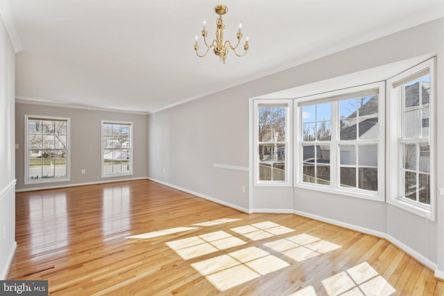 spare room featuring light wood-style flooring, baseboards, an inviting chandelier, and ornamental molding