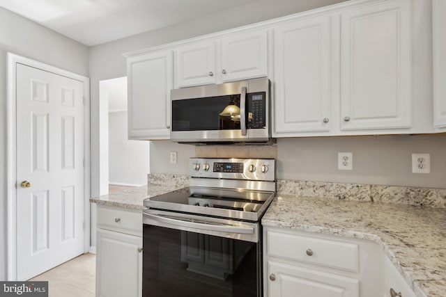 kitchen with white cabinetry, light stone counters, and appliances with stainless steel finishes