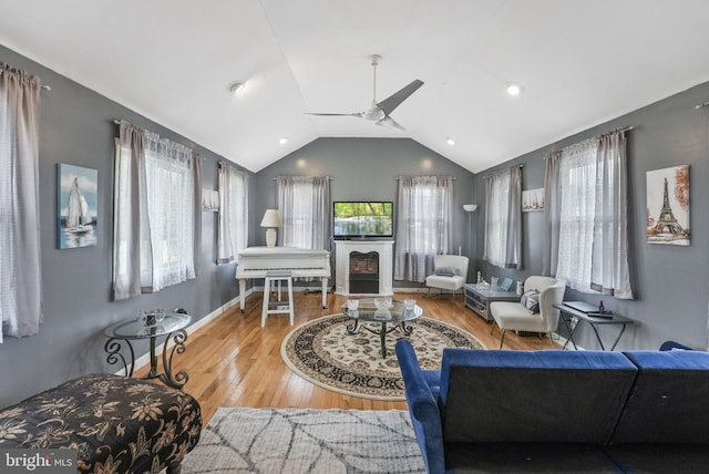 living area featuring lofted ceiling, baseboards, a ceiling fan, and wood finished floors