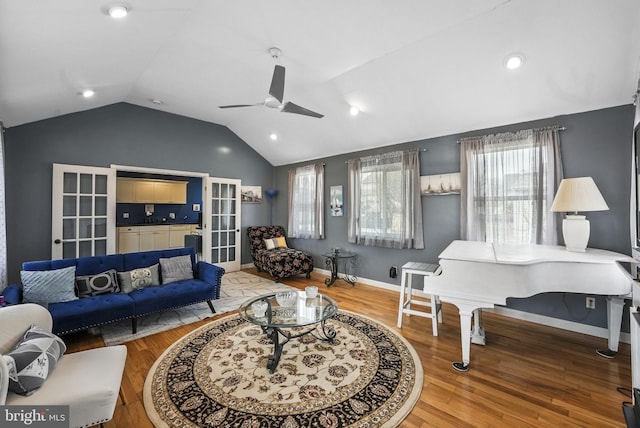 living room with ceiling fan, baseboards, vaulted ceiling, and wood finished floors