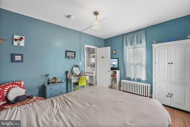 bedroom with radiator heating unit and wood finished floors