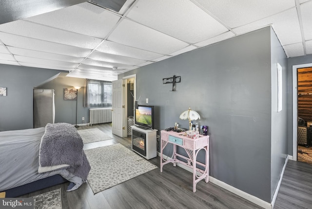 bedroom with a paneled ceiling, radiator heating unit, and wood finished floors