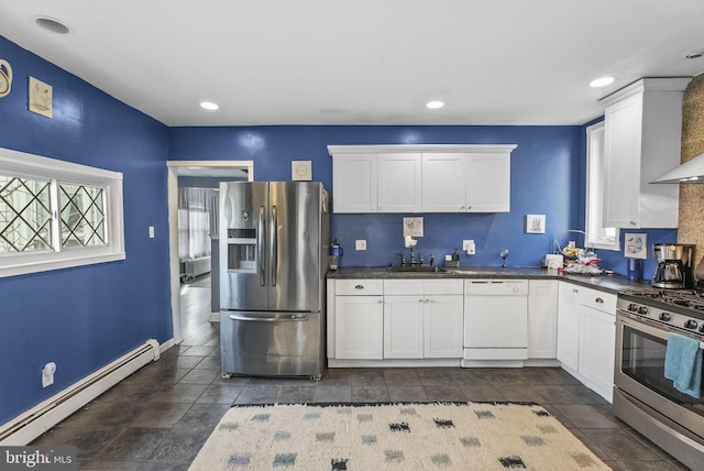 kitchen featuring white cabinets, dark countertops, a baseboard radiator, appliances with stainless steel finishes, and a sink