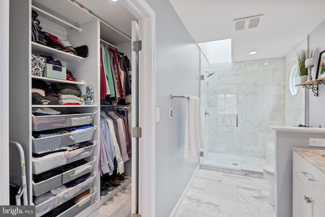 bathroom with marble finish floor, a shower stall, toilet, and a spacious closet