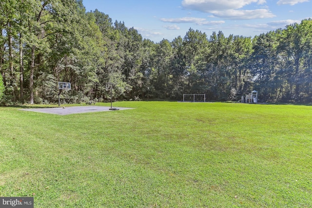 view of yard featuring community basketball court and a wooded view