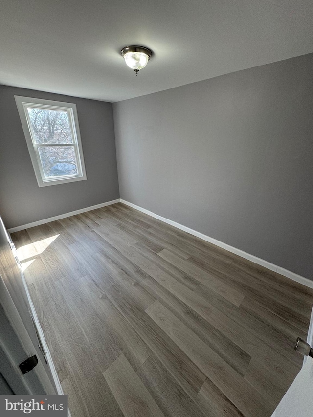 spare room featuring dark wood finished floors and baseboards