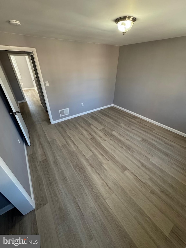 empty room with visible vents, baseboards, and wood finished floors