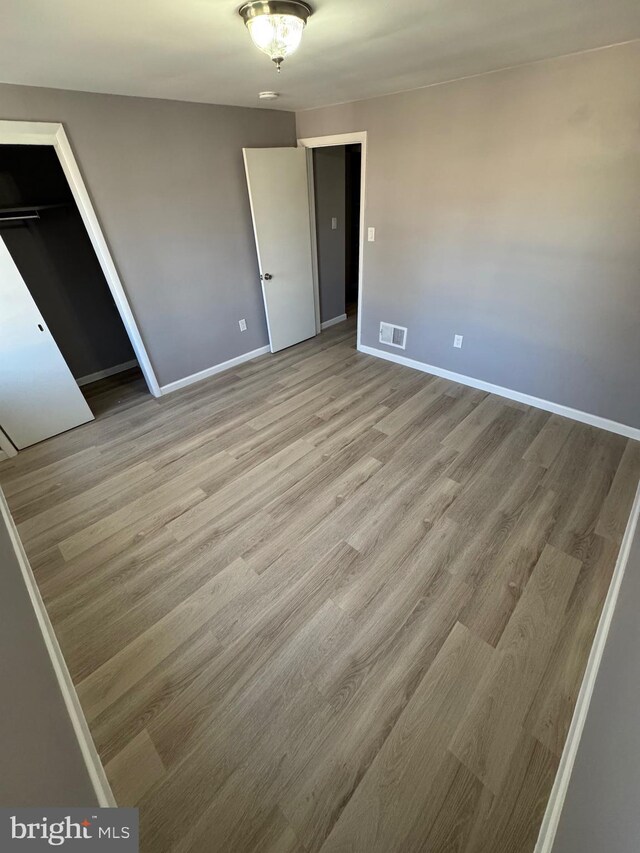 unfurnished bedroom with visible vents, baseboards, and wood finished floors