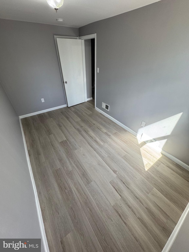 unfurnished room featuring visible vents, baseboards, and wood finished floors