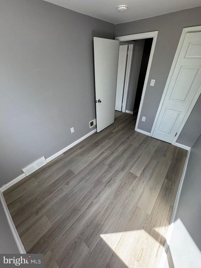 unfurnished bedroom featuring wood finished floors, visible vents, and baseboards