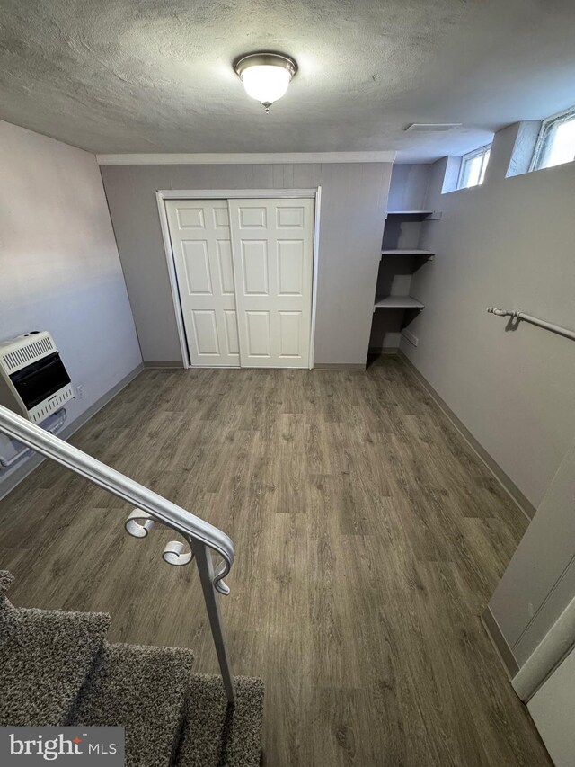 unfurnished bedroom featuring a closet, heating unit, a textured ceiling, and wood finished floors