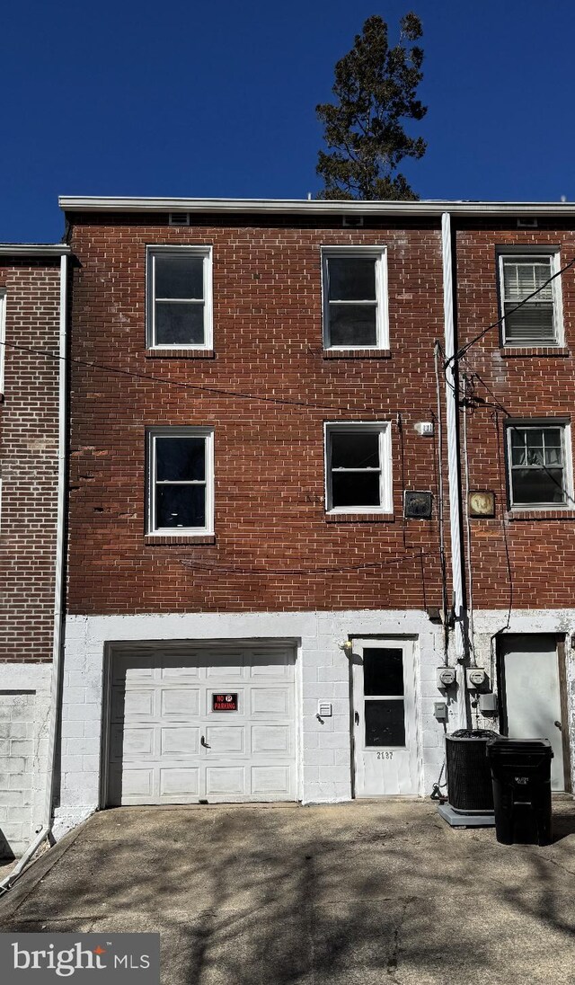 rear view of house with brick siding, cooling unit, and a garage