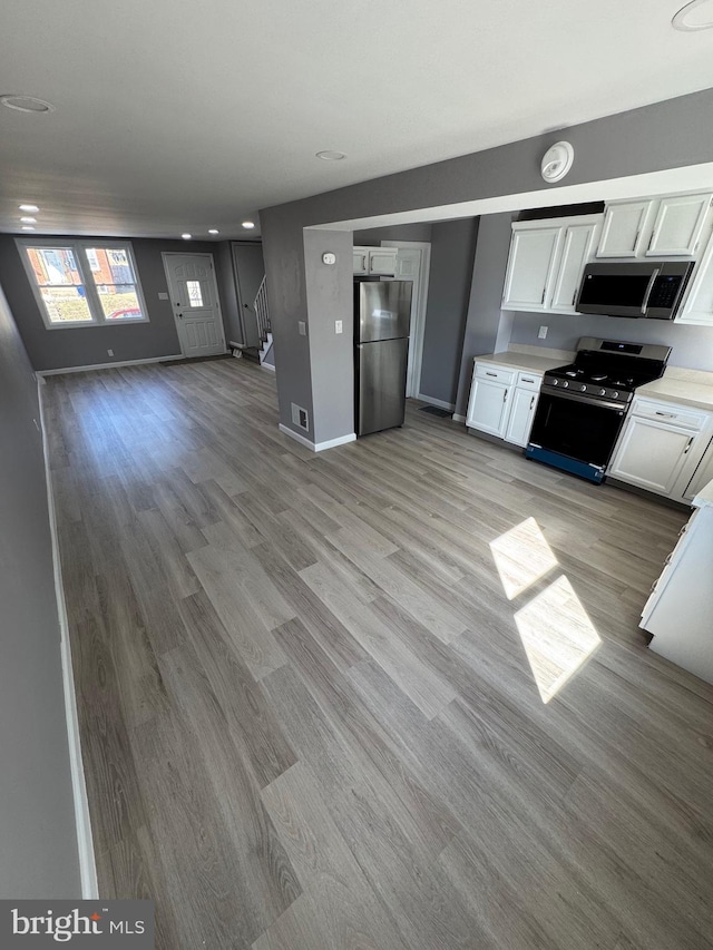 kitchen with white cabinetry, light countertops, light wood-style floors, and stainless steel appliances