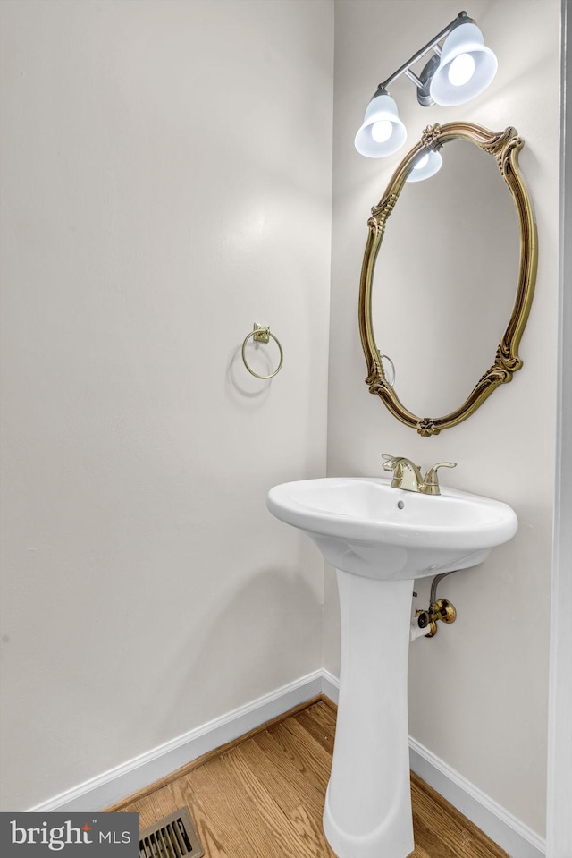 bathroom featuring a sink, baseboards, visible vents, and wood finished floors