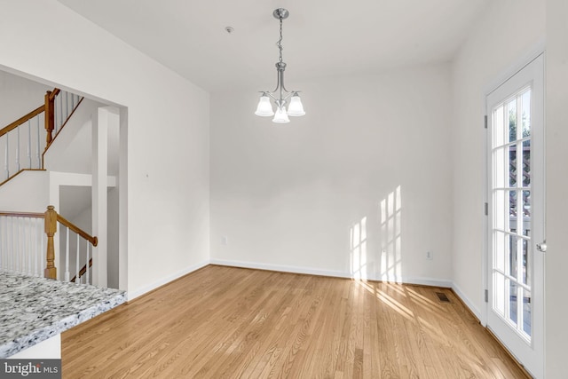 unfurnished dining area with a chandelier, visible vents, baseboards, stairway, and light wood finished floors