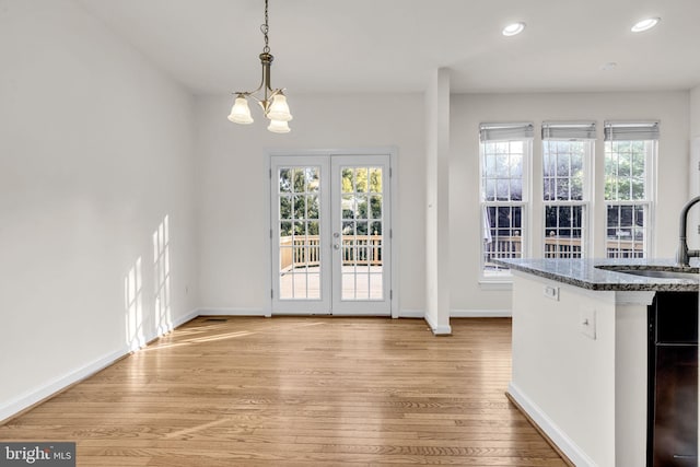 unfurnished dining area featuring light wood-type flooring, plenty of natural light, a sink, and baseboards